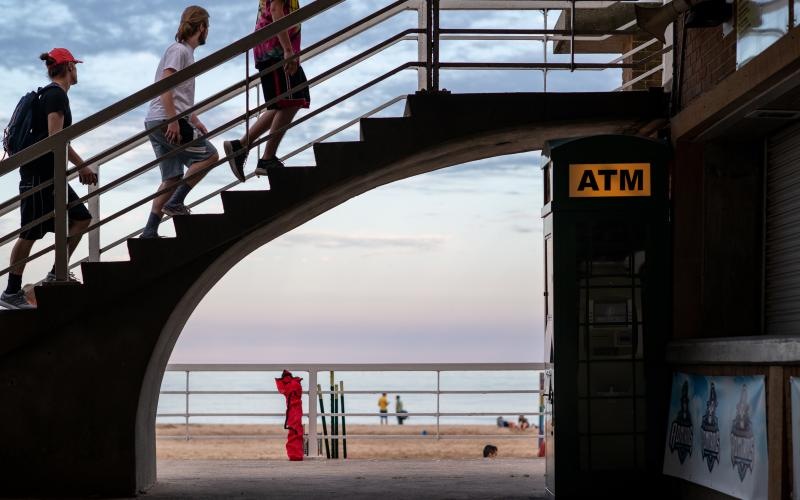 people walking upstairs over a boardwalk next to the beach