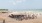 Busy beach cabana with people, volleyball, and lake
